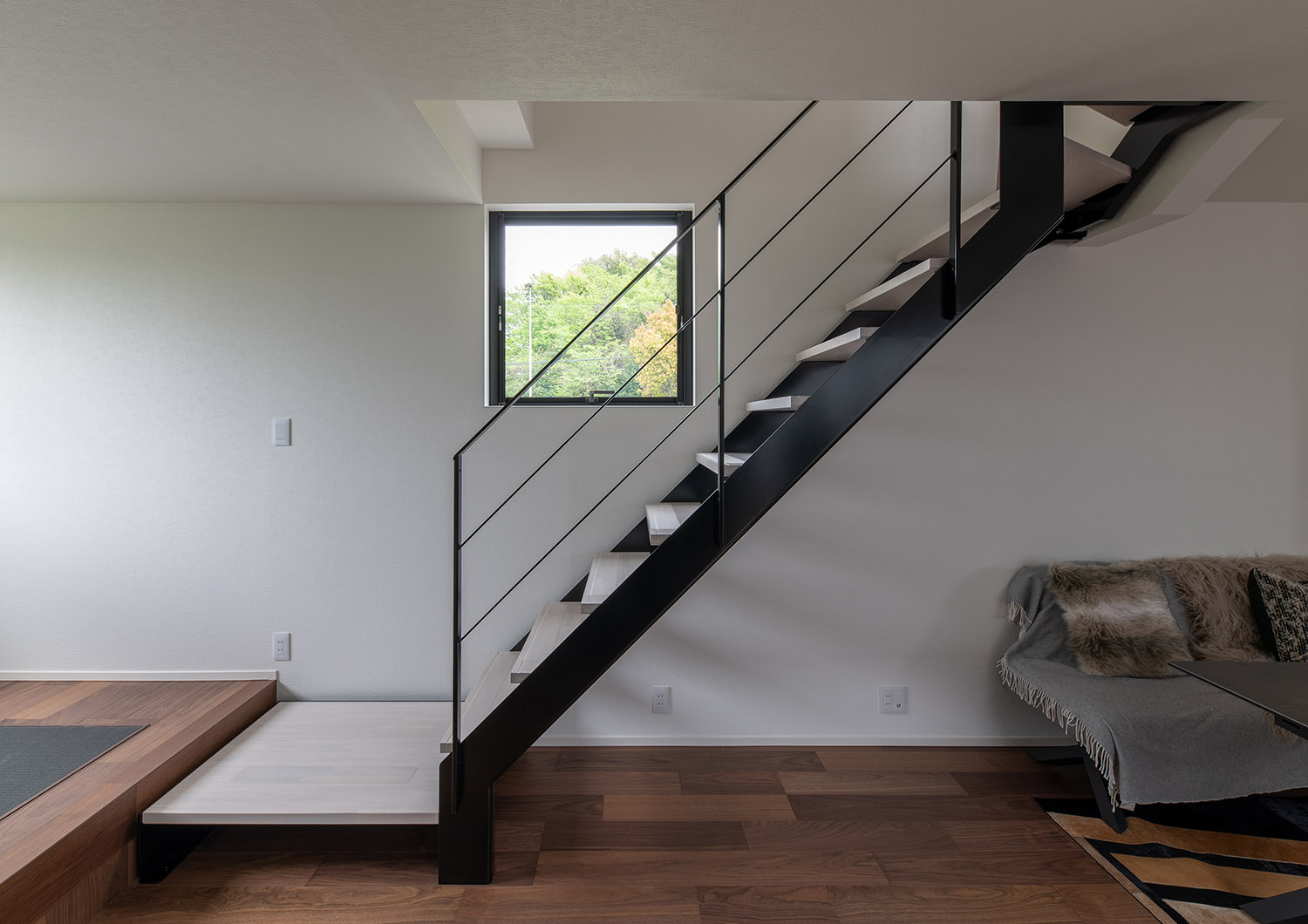 リビングイン階段が付けられた壁に正方形の窓が設けられている様子・デザイン住宅 注文住宅・デザイン住宅建築実例_『CASE751 Contarst』_階段