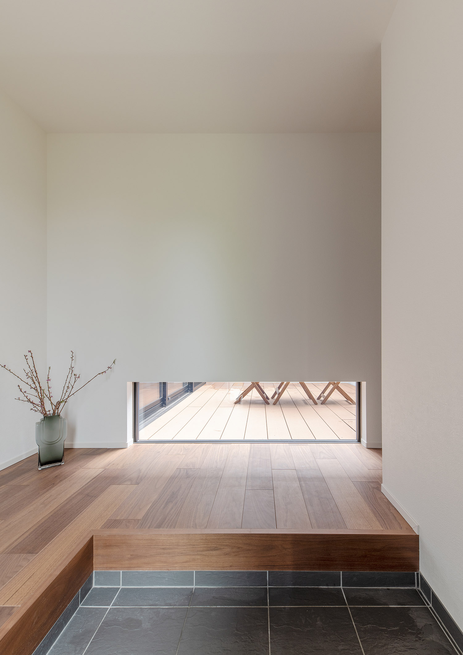 グレーのタイルの玄関の正面に地窓が設けられている様子・デザイン住宅 注文住宅・デザイン住宅建築実例_『CASE751 Contarst』_玄関