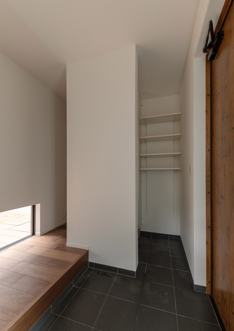 シューズインクローゼットが繋がったグレーのタイルの玄関・デザイン住宅 注文住宅・デザイン住宅建築実例_『CASE751 Contarst』_玄関