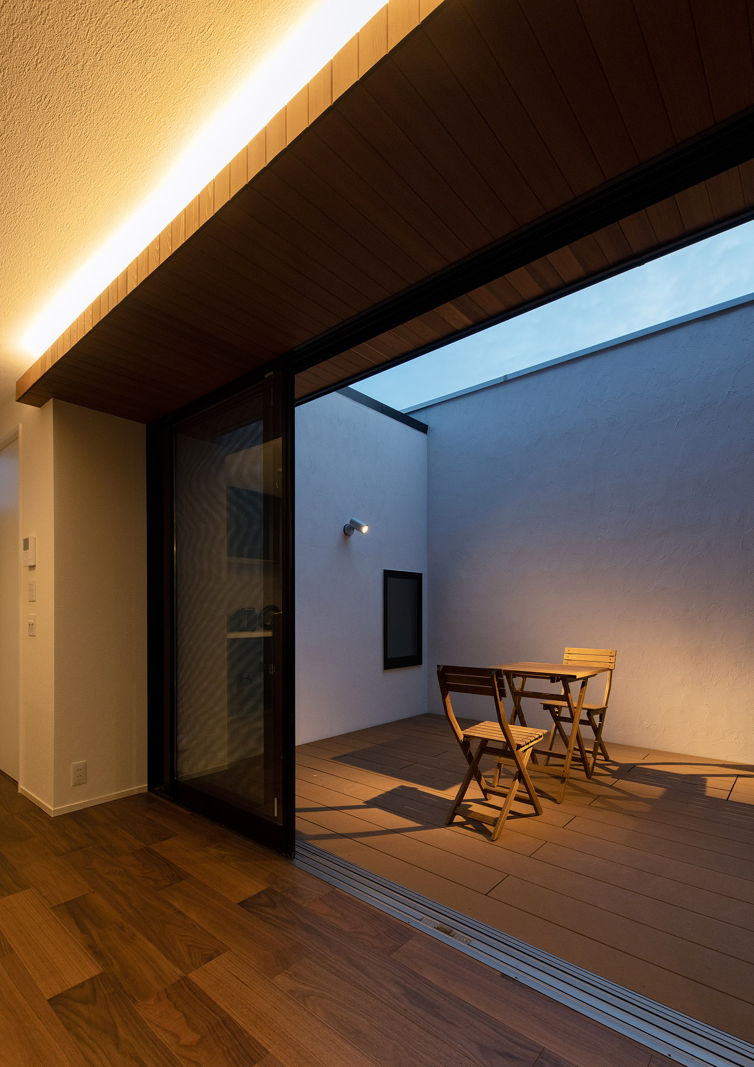 中庭と繋がる窓の窓際の壁に沿って、間接照明が取り付けられたLDK・デザイン住宅 注文住宅・デザイン住宅建築実例_『CASE751 Contarst』_中庭