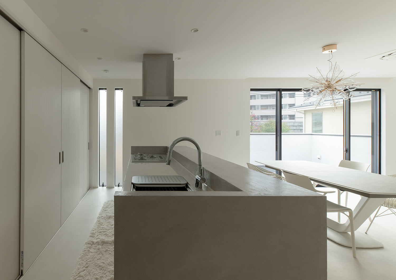 コンクリートのアイランドキッチンがある、バルコニーに面した大開口窓があるLDK・デザイン住宅 注文住宅・デザイン住宅建築実例_『CASE752 as CANVAS』_キッチン