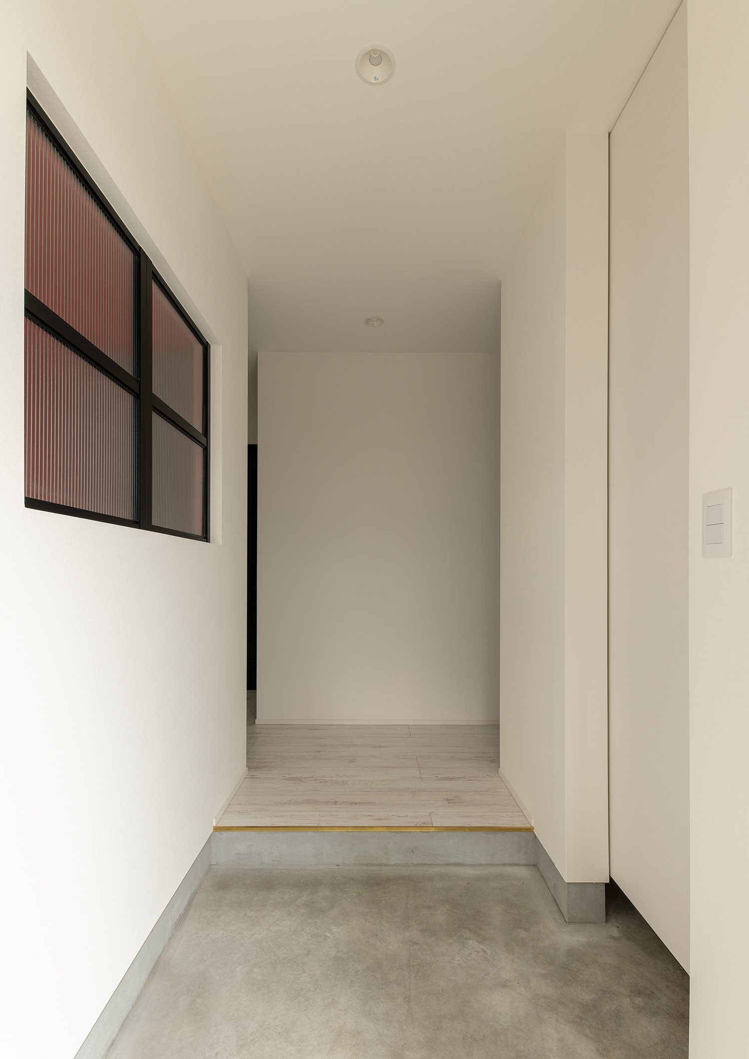 白い壁に室内窓があるモルタルの玄関・デザイン住宅 注文住宅・デザイン住宅建築実例_『CASE752 as CANVAS』_玄関