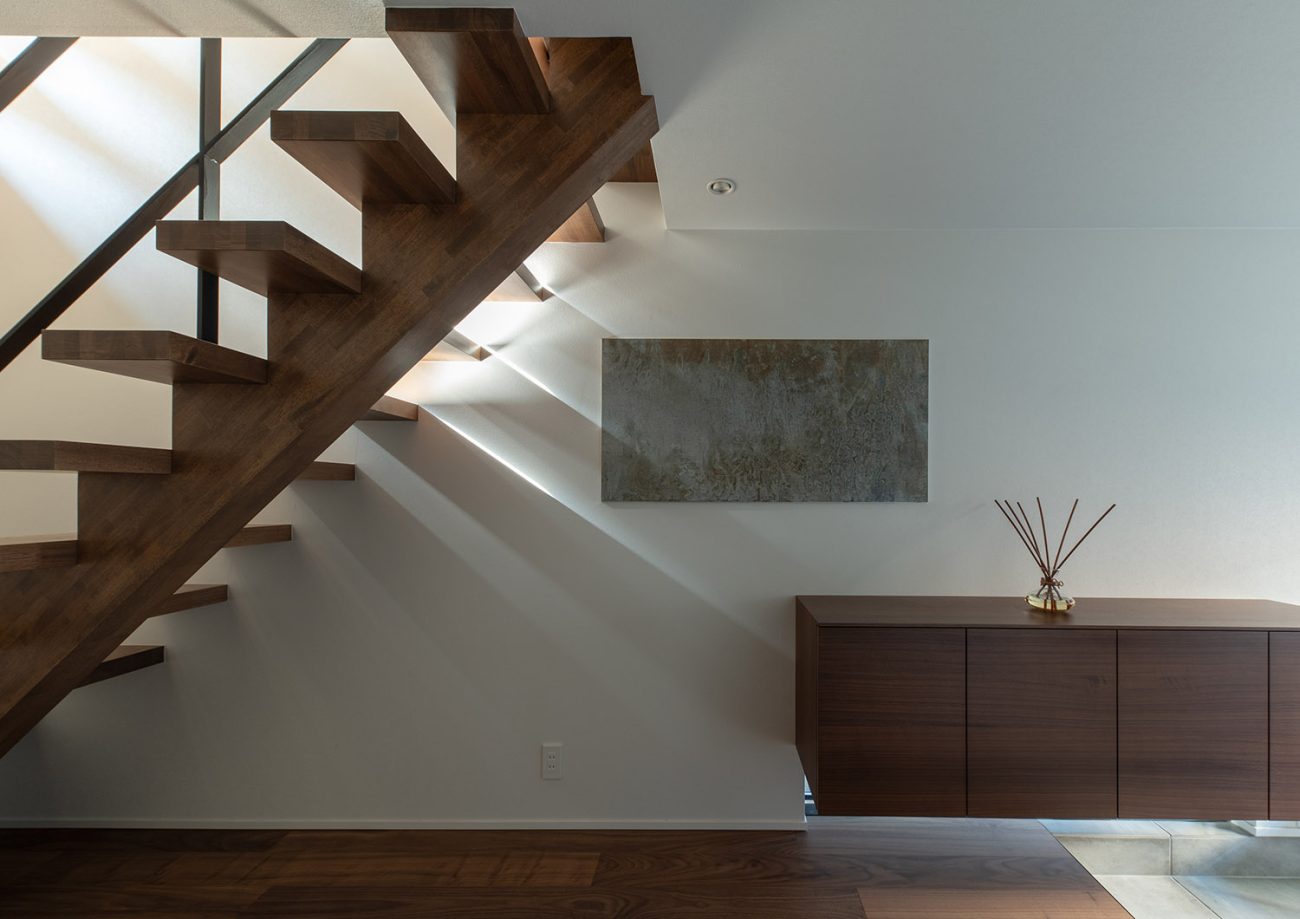 下に地窓を設けた浮いたデザインのシューズボックスや、木のスケルトン階段がある廊下・デザイン住宅 注文住宅・デザイン住宅建築実例_『CASE753 円佇の家（えんていのいえ）』_玄関