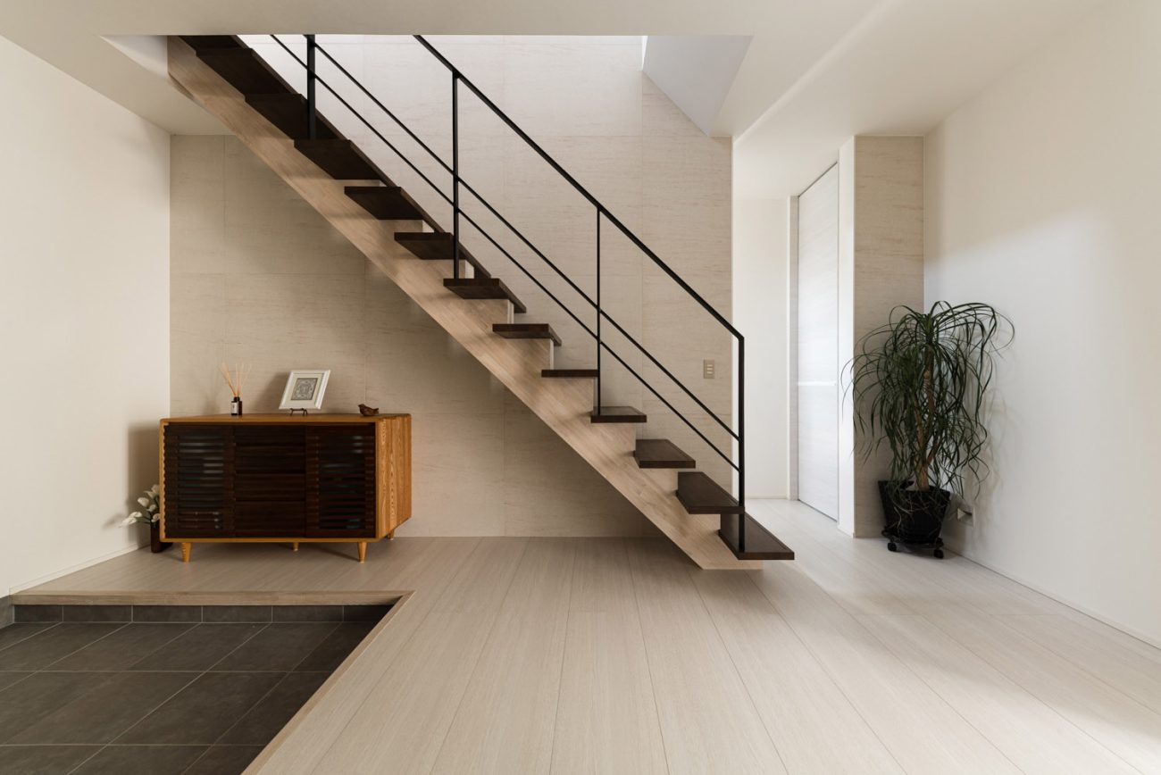 白いフローリングのフロアにダークブラウンのスケルトン階段がある様子・デザイン住宅 注文住宅・デザイン住宅建築実例_『CASE754 首途（かどで）の家』_玄関