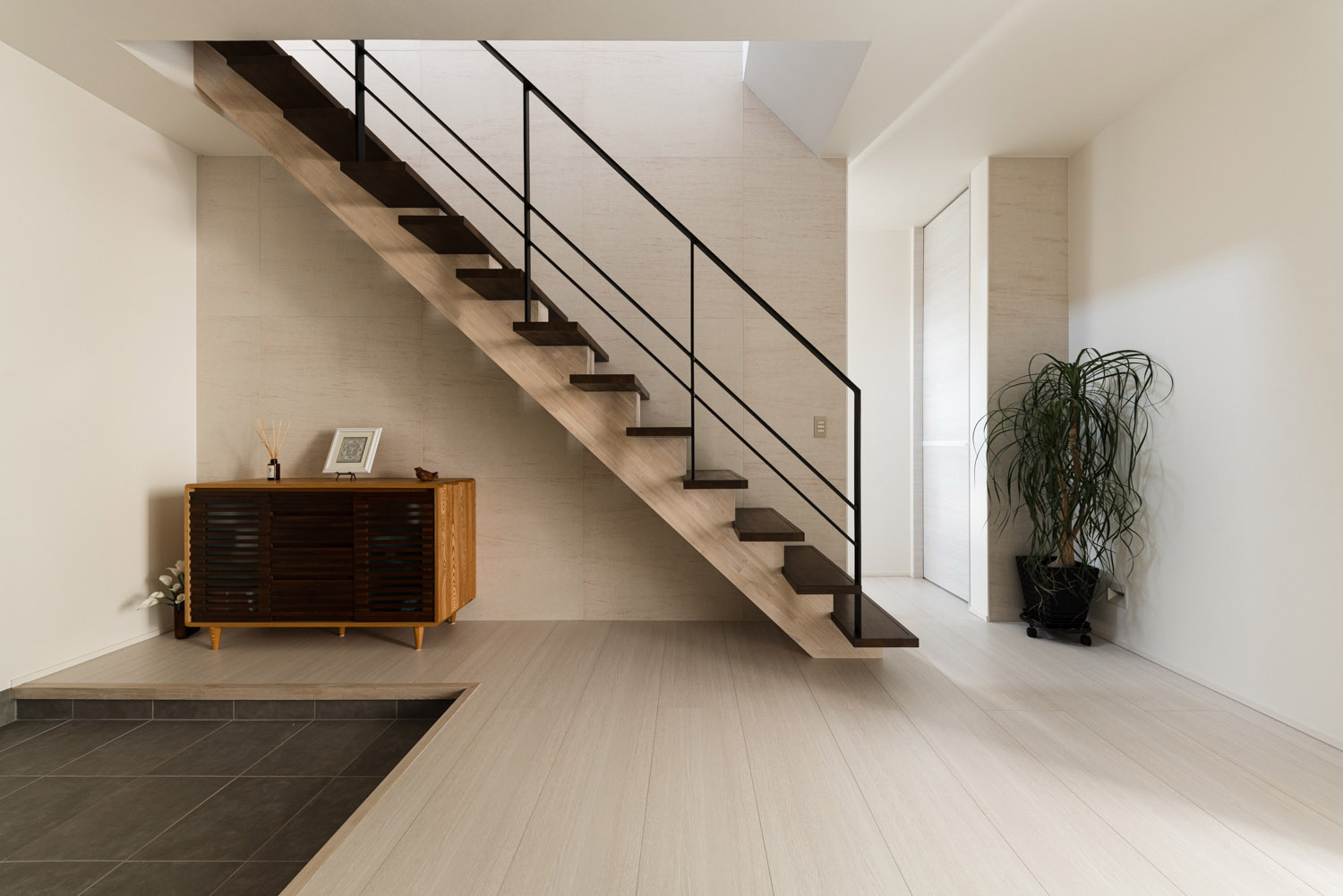 白いフローリングのフロアにダークブラウンのスケルトン階段がある様子・デザイン住宅 注文住宅・デザイン住宅建築実例_『CASE754 首途(かどで)の家』_玄関