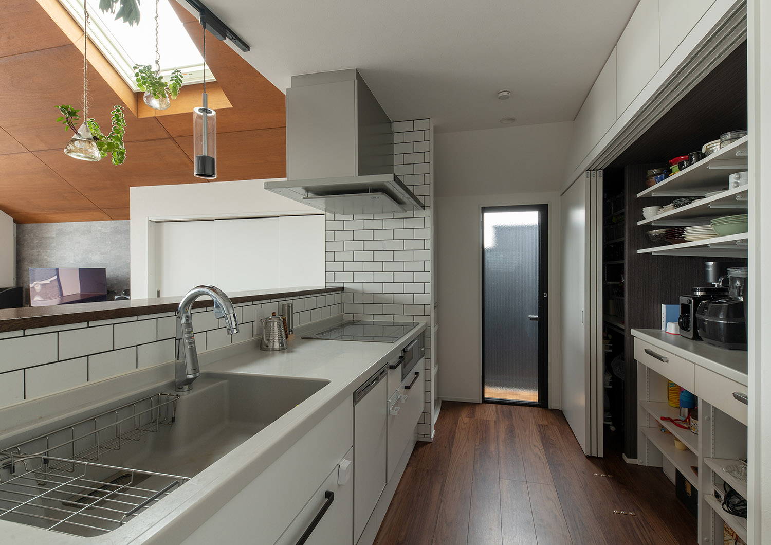 背面のカップボードが引き戸で隠せるようになっている縦長扉のあるキッチン・デザイン住宅 注文住宅・デザイン住宅建築実例_『CASE755 山際の家（やまぎわのいえ）』_キッチン