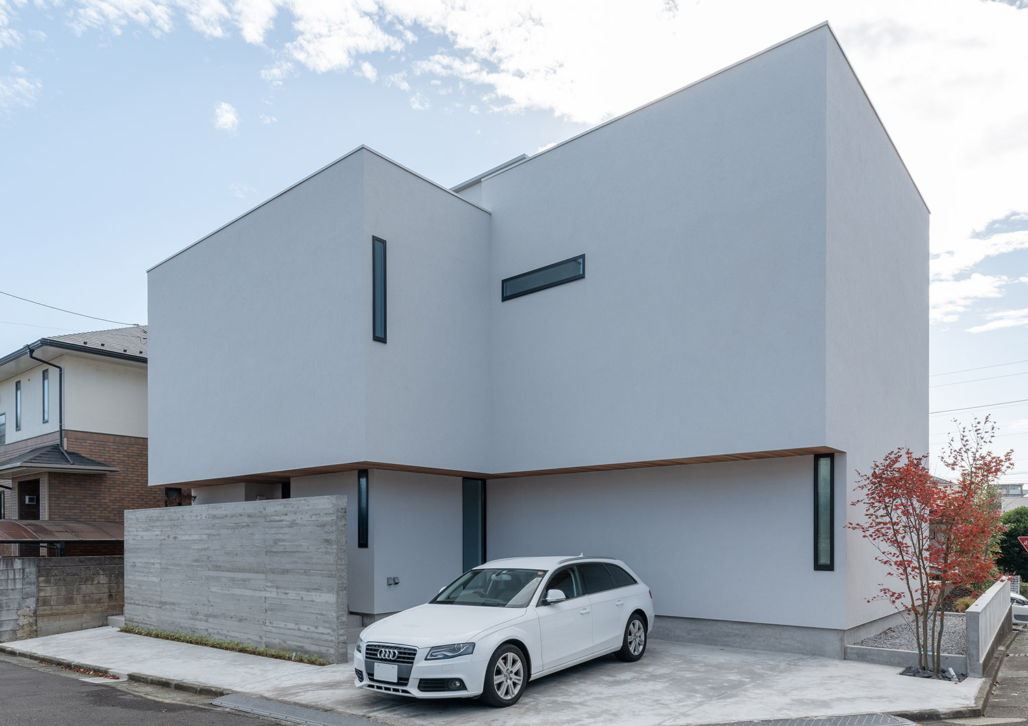 小さめのスリット窓がある白いキューブ状の家の前に白い車が一台止められた様子・デザイン住宅 注文住宅・デザイン住宅建築実例_『CASE756 utsuwa』_外観