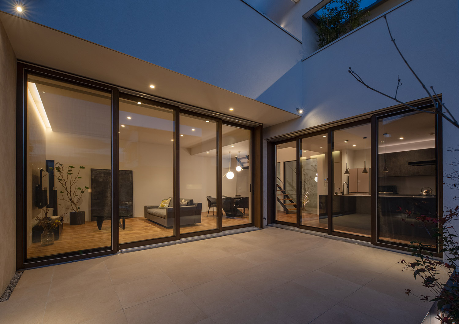 壁や軒天井に照明が取り付けられた、LDKと繋がるタイルの中庭・デザイン住宅 注文住宅・デザイン住宅建築実例_『CASE756 utsuwa』_テラス・バルコニー