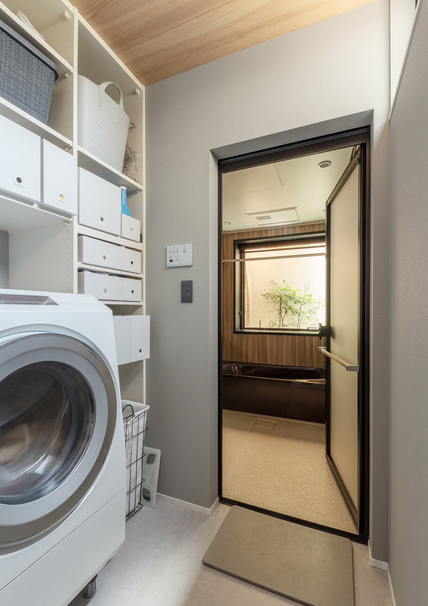 洗濯機スペースの回りに収納棚があり、隣に浴室がある様子・デザイン住宅 注文住宅・デザイン住宅建築実例_『CASE757 トキノエンガワ』_浴室・洗面所