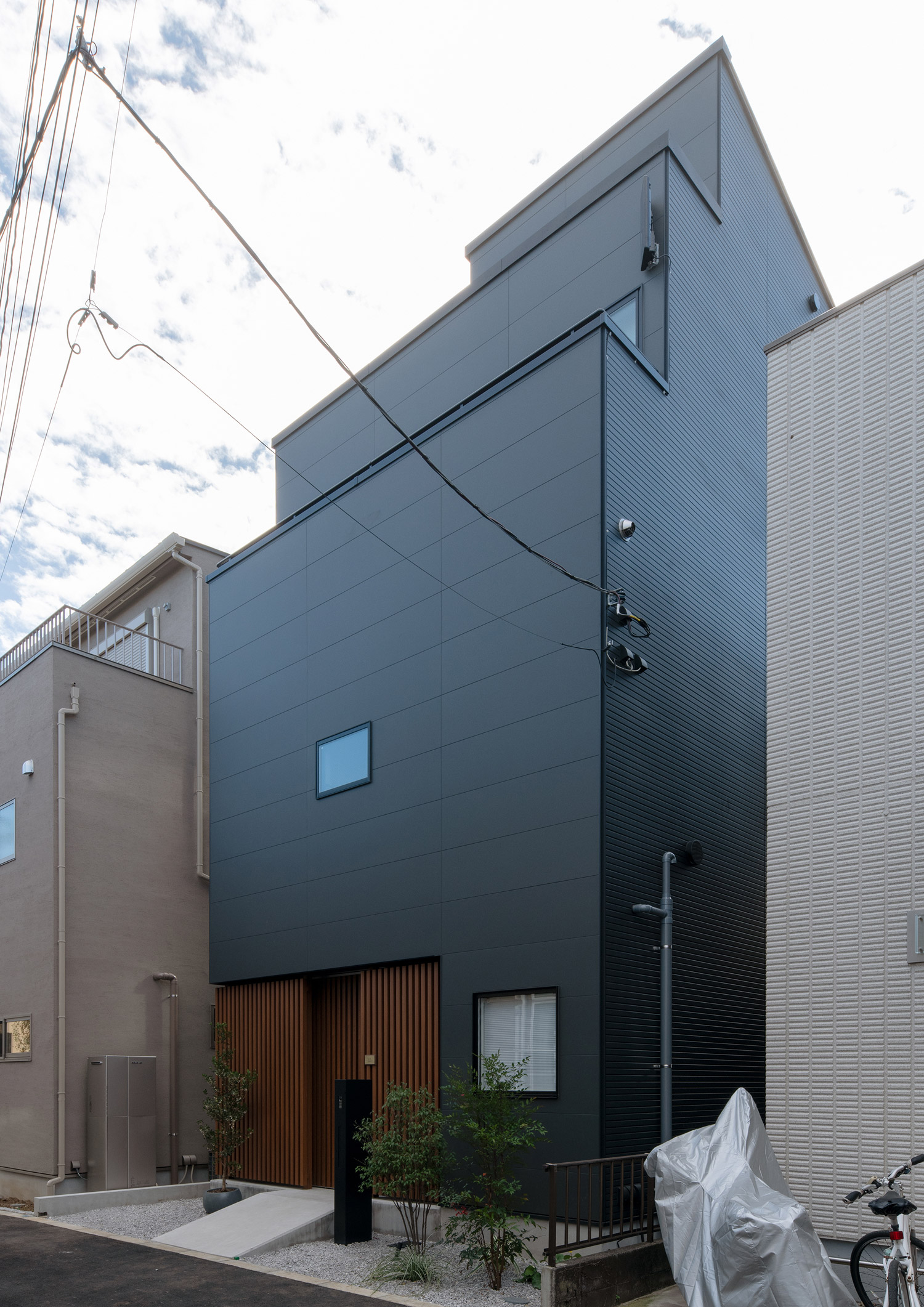 住宅街に建つ黒い外壁の三階建て住宅を斜めから見た様子・デザイン住宅 注文住宅・デザイン住宅建築実例_『CASE753 円佇の家（えんていのいえ）』_外観