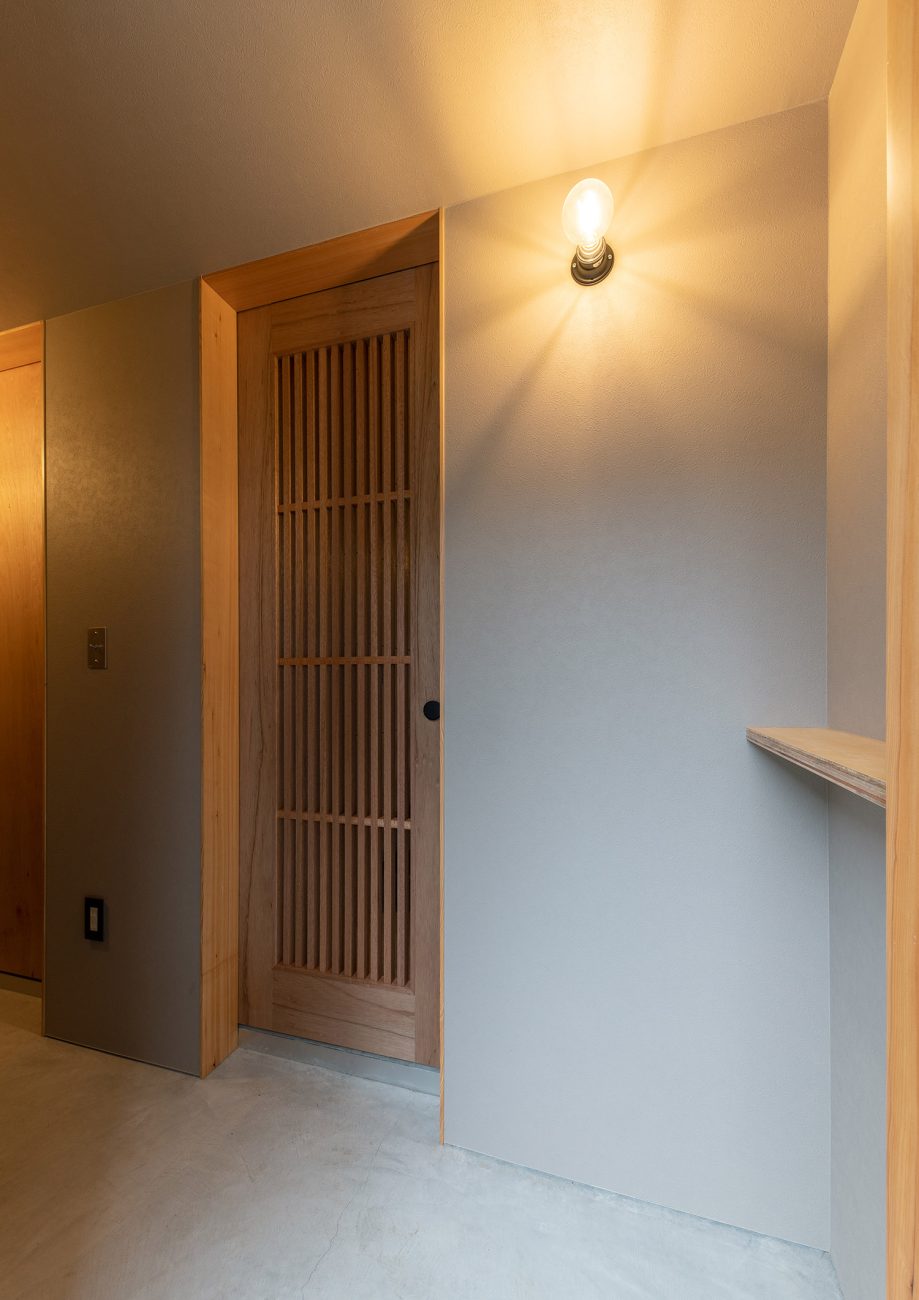 壁に照明を取り付けた和風の扉がある玄関・デザイン住宅 注文住宅・デザイン住宅建築実例_『CASE760 自然体の家』_玄関
