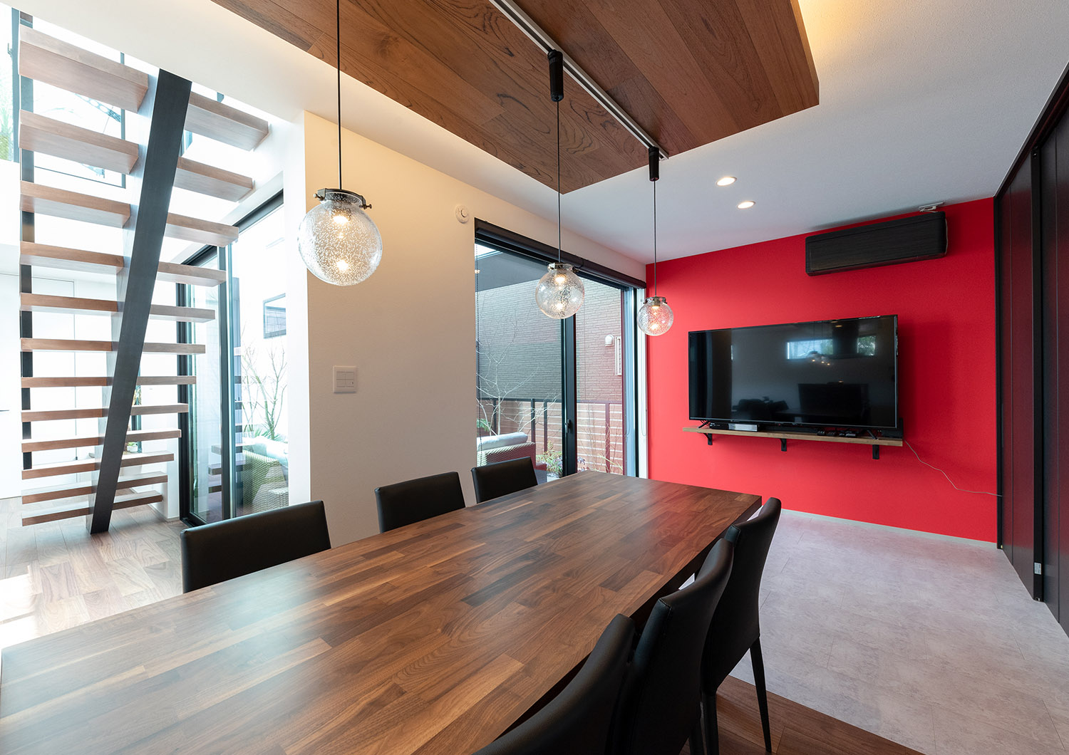 赤いアクセントクロスにテレビを取り付けた木のダイニングテーブルがあるLDK・デザイン住宅 注文住宅・デザイン住宅建築実例_『CASE765 イロ色のイエ』_LDK