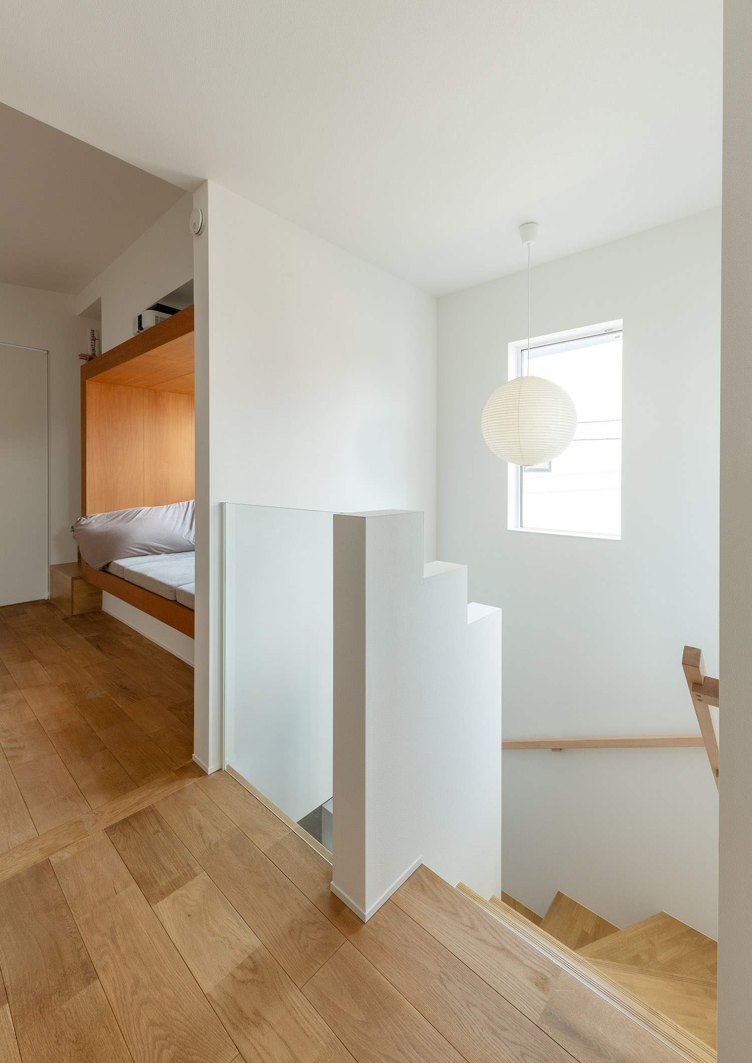 壁の一部をガラスにして丸いペンダントライトがアクセントになった階段室・デザイン住宅 注文住宅・デザイン住宅建築実例_『CASE770 籠(こ)もれる家』_階段