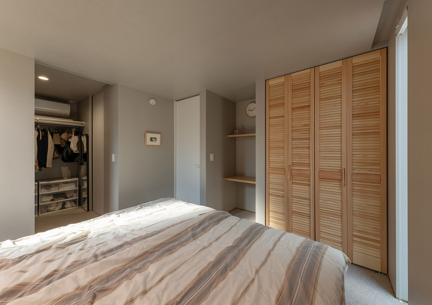 ウォークインクローゼットと木の扉付きのクローゼットがある広々とした寝室・デザイン住宅 注文住宅・デザイン住宅建築実例_『CASE770 籠(こ)もれる家』_寝室