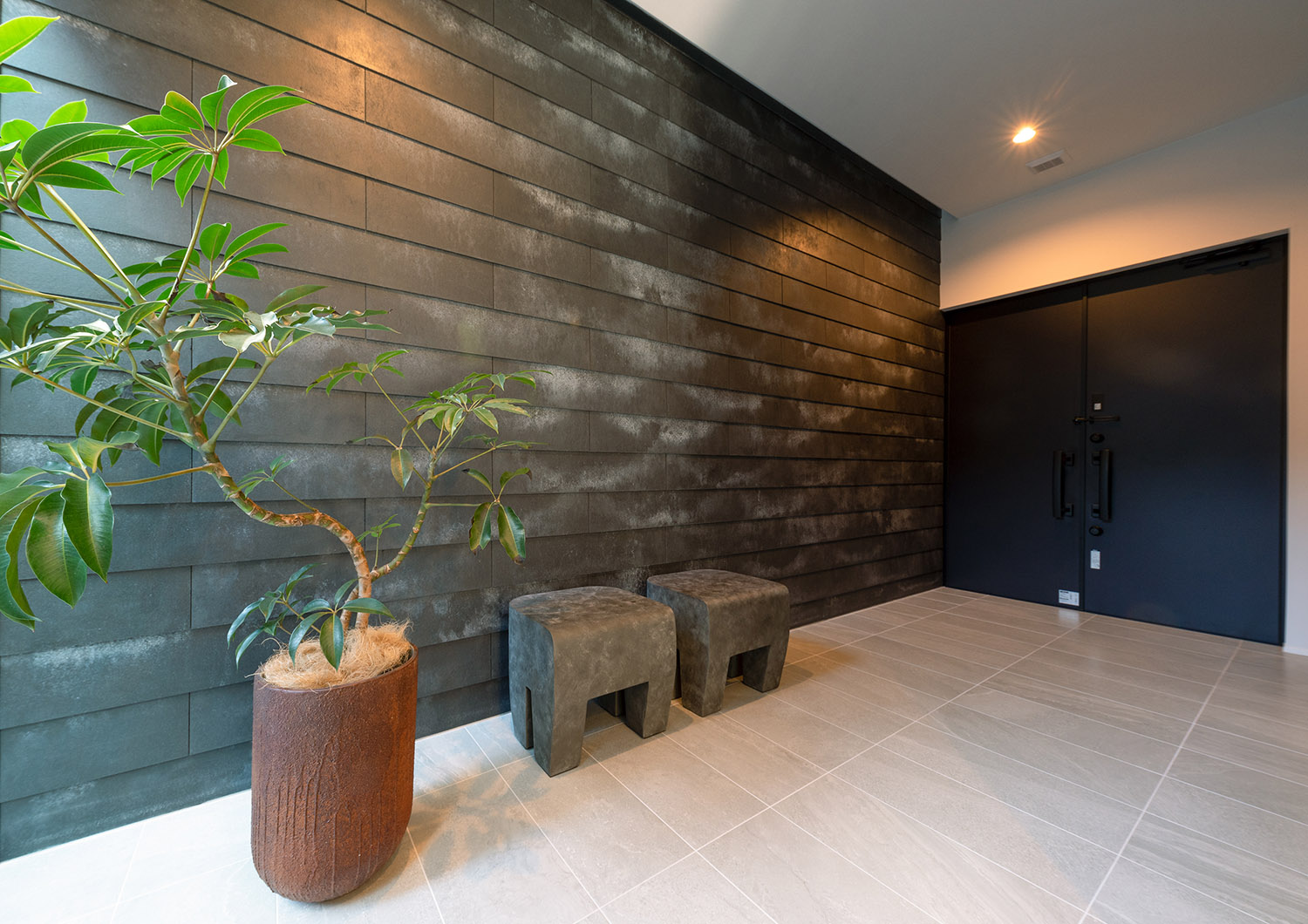 グレーのタイル壁で、植栽が置かれた広くておしゃれな玄関ポーチ・デザイン住宅 注文住宅・デザイン住宅建築実例_『CASE771 VOIDS』_玄関