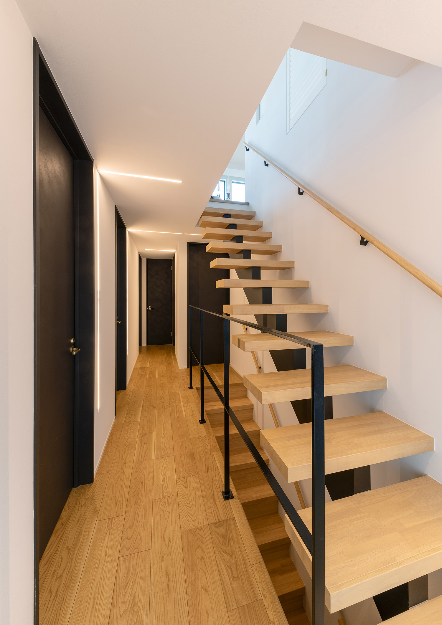 黒いアイアンの手すりを取り付けたスケルトン階段のそばにある廊下・デザイン住宅 注文住宅・デザイン住宅建築実例_『CASE769 othello』_階段