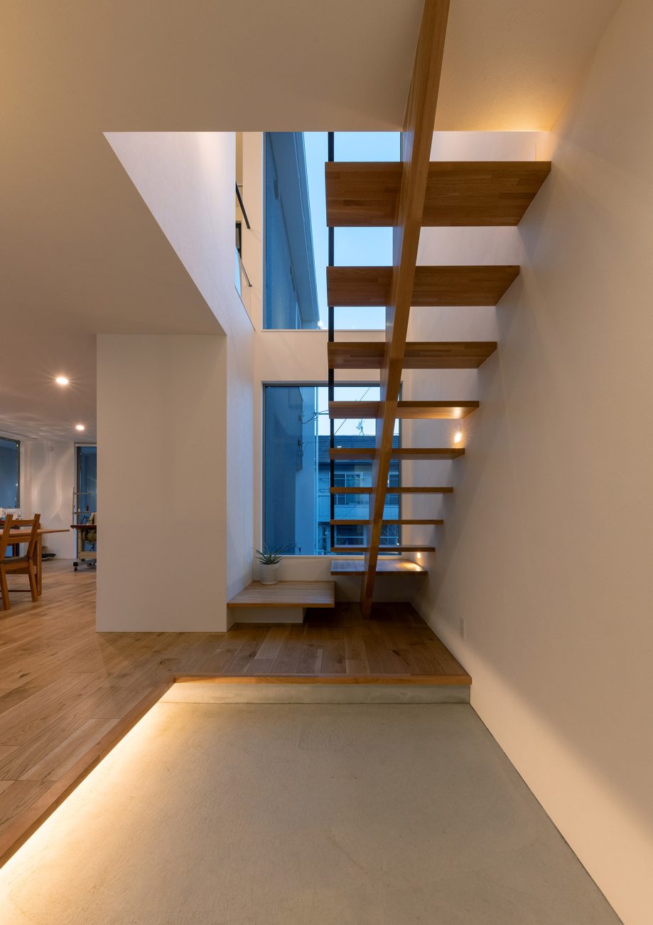 足元に間接照明が取り付けられたスケルトン階段が横切るモルタルの玄関・デザイン住宅 注文住宅・デザイン住宅建築実例_『CASE775 二色の陽射し』_玄関・階段