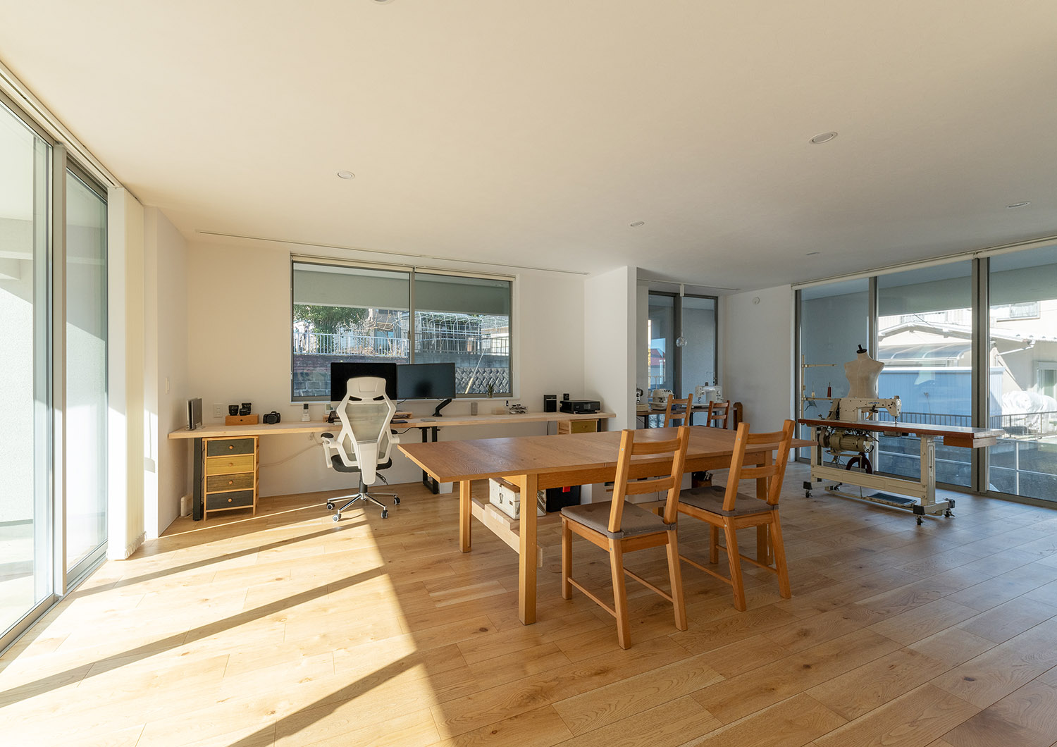 壁付けデスクや木の大きなテーブルがある大きな窓付きの作業部屋・デザイン住宅 注文住宅・デザイン住宅建築実例_『CASE775 二色の陽射し』_仕事部屋